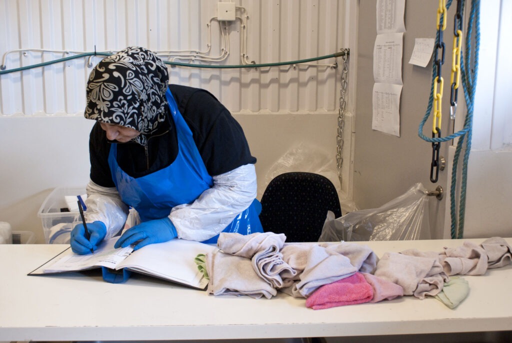 Kvinna som arbetar med textilier vid ett bord.