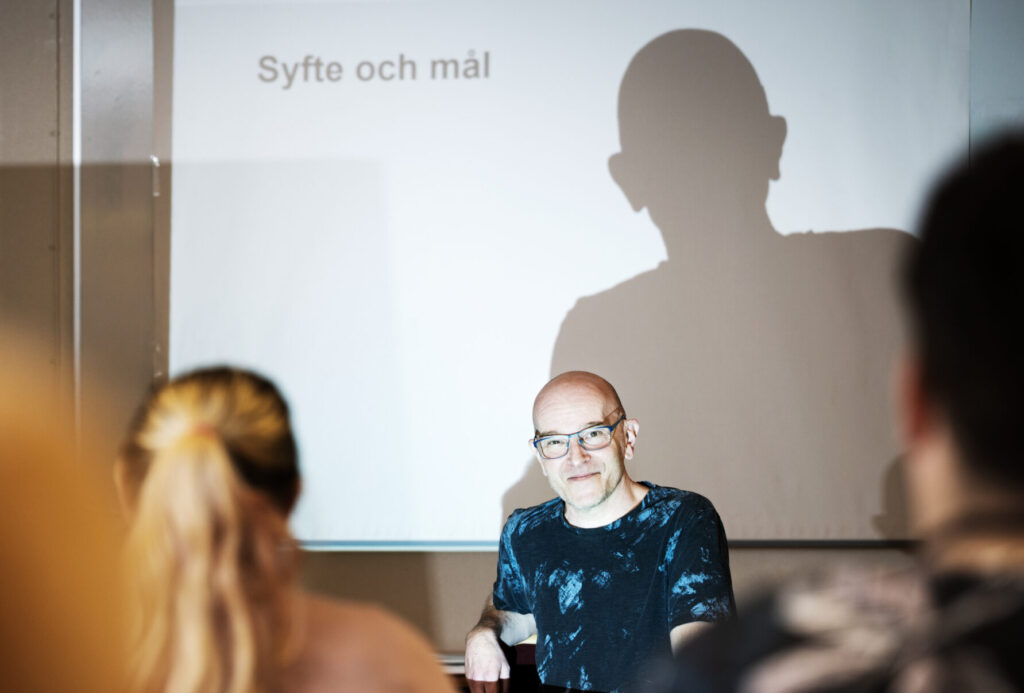 Bild från klassrummet. Man sitter framför whiteboard med texten "Syfte och mål".