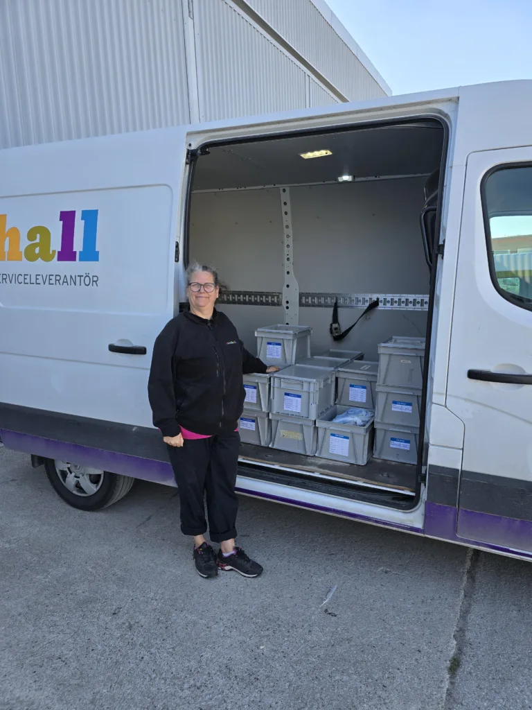 Sanna står vid sin bil. Backarna med lokalvårdsmaterial är inlastade.