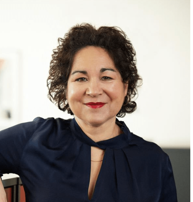 Samhalls direktör för HR & kommunikation ler och tittar in i kameran. Hon har mörkt, lockigt hår och bär en svart blus.