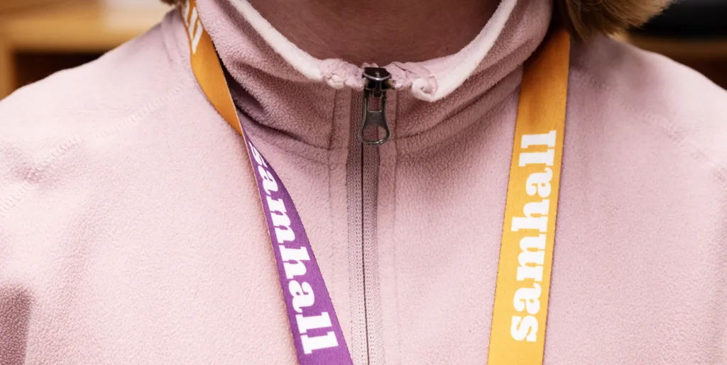 Inzoomat rosa och gult nyckelband med texten Samhall i vitt.