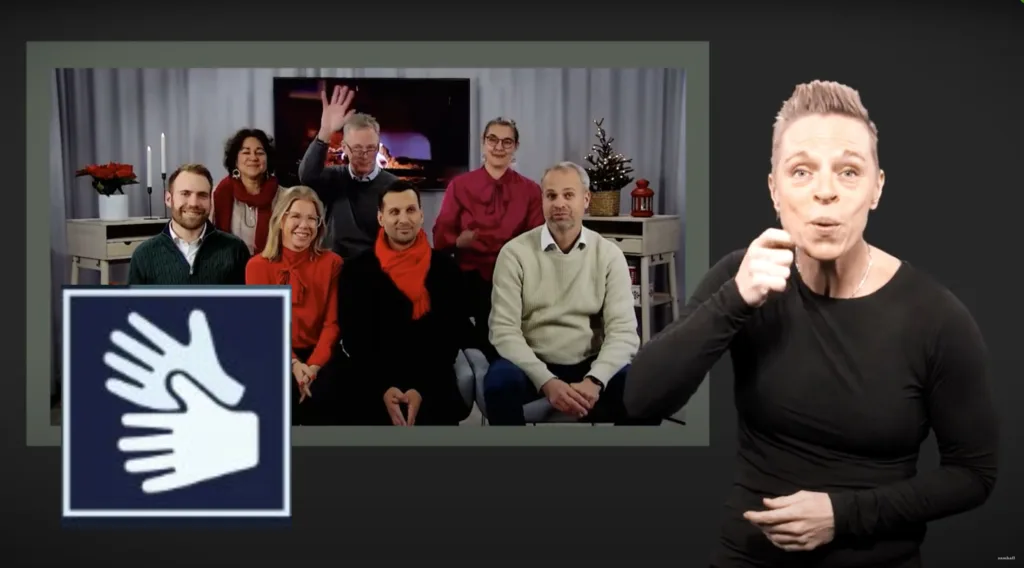 Teckenspråkstolk i fokus. Bakom henne en skärm som visar Samhalls företagsledning.