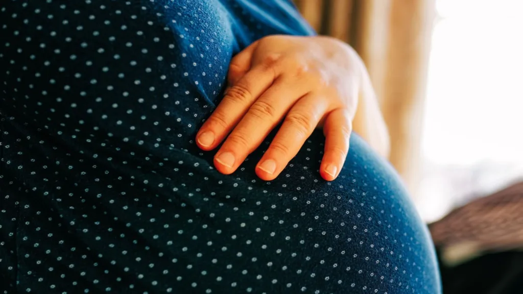 En kvinna har handen på sin gravidmage.