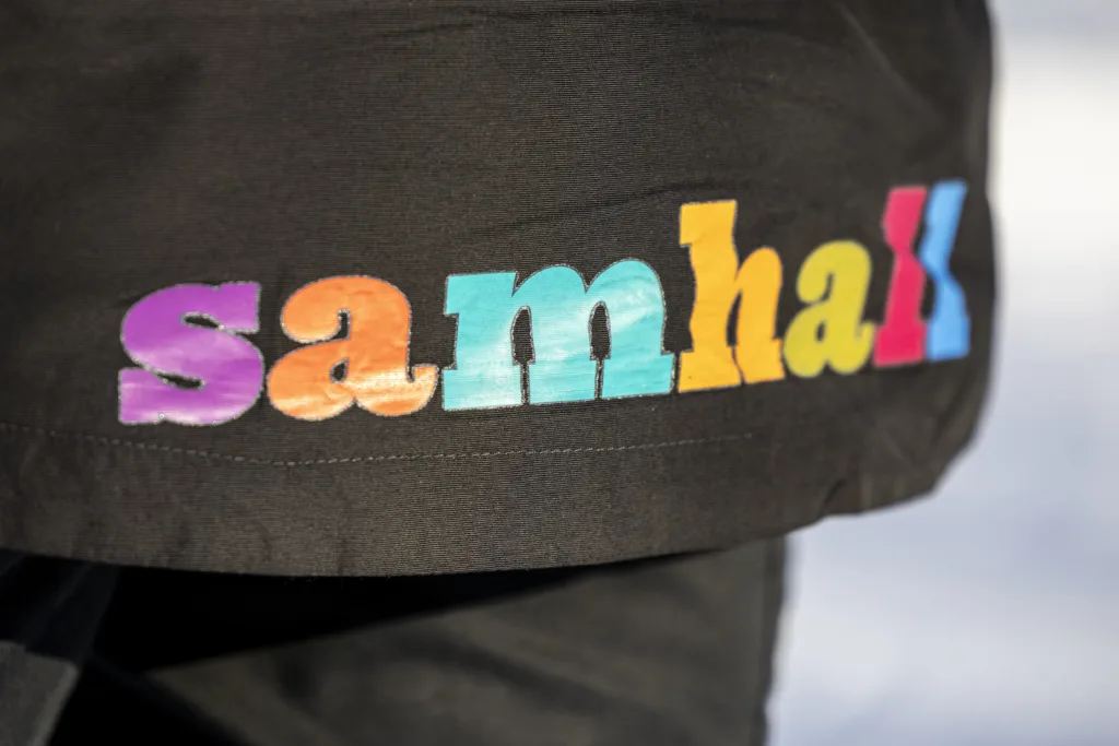 Samhalls färgglada logga på en mörk jacka.