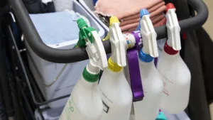 Inzoomade flaskor med rengöring. Flaskorna hänger på en städvagn.